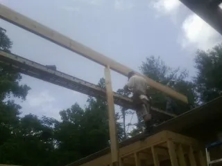 Carpenter setting a ridge beam over a new addition frame — Ice Dam Removal by Roofing Brothers in Mastic Beach