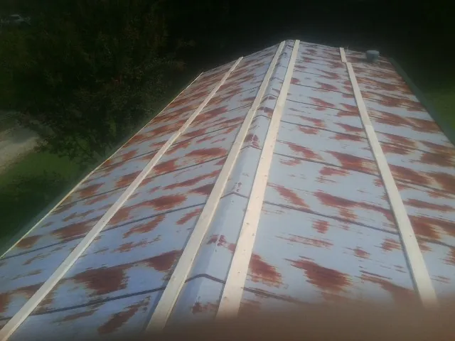 Rusted metal roof panels with new wood purlins before replacement — Storm Damage Roof Repair in Mastic Beach by Roofing Brothers