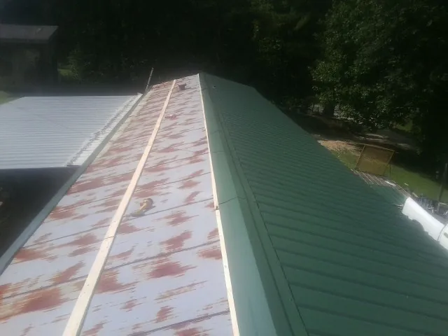Old rusted panels beside newly installed green metal roofing — Wind Damage Roof Repair by Roofing Brothers in Mastic Beach