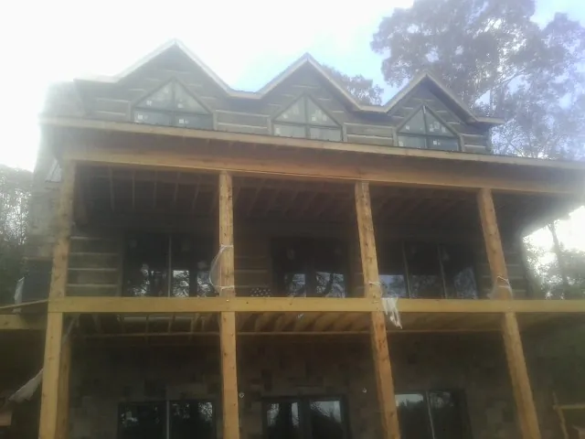 Dormers and porch framing on a large log home under construction — Roof Coating work by our crew in Mastic Beach