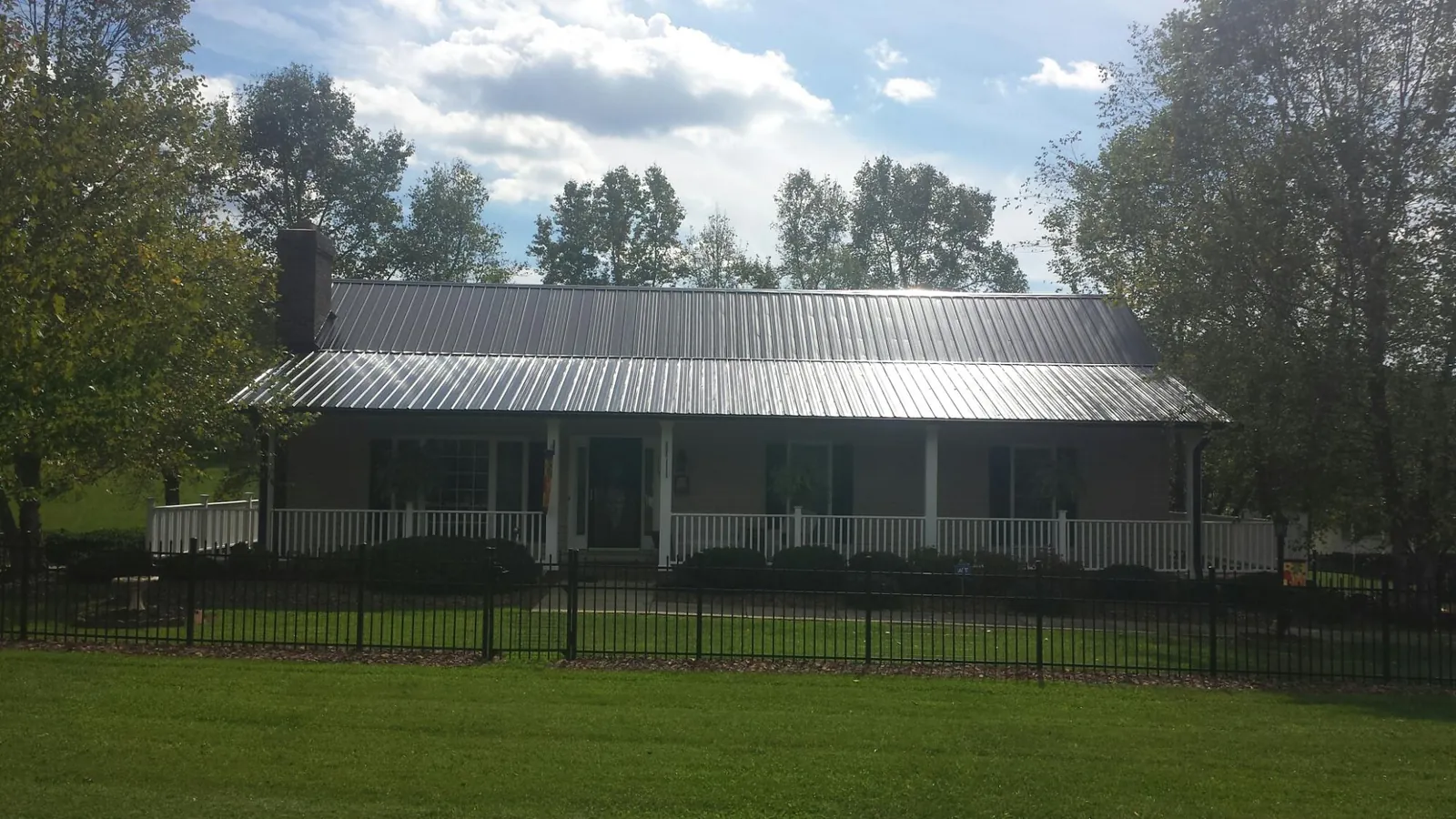 Gray metal roof on a brick ranch with a full width front porch — Gutter Guard Installation work by our crew in Mastic Beach