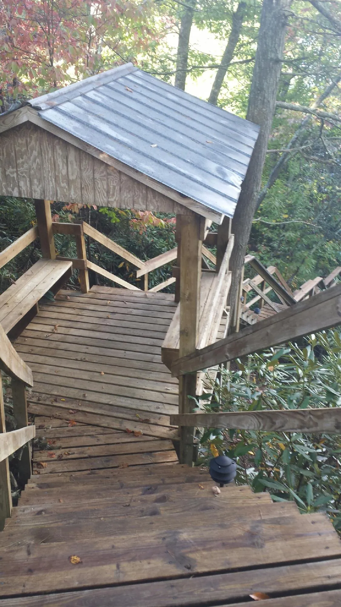 Metal roofed shelter over wooden steps on a wooded walkway — Skylight Repair & Installation work by our crew in Mastic Beach